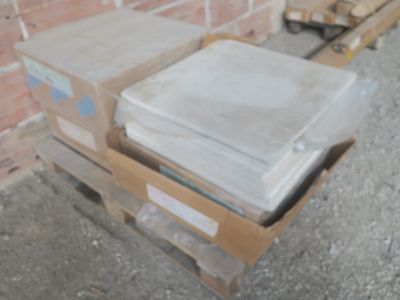 une pile de cartons posée sur une palette devant un mur de briques