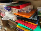 many folders stacked on a shelf in a cluttered room