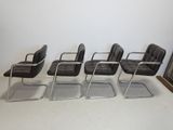 four black leather office chairs in a row in front of a framed picture
