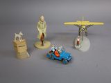 plusieurs figurines représentant des personnages et un avion, posées sur une surface grise