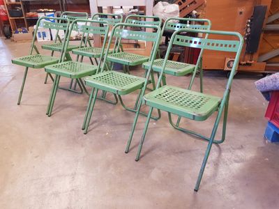 de nombreuses chaises vertes dans une pièce où il y a beaucoup d'objets par terre