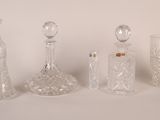 quatre bouteilles en verre et un vase en verre posés sur une surface blanche
