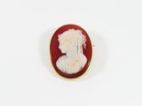 un gros plan sur une broche rouge et blanche représentant le profil d'une femme