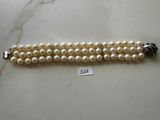 a close up of a bracelet with pearls on a table