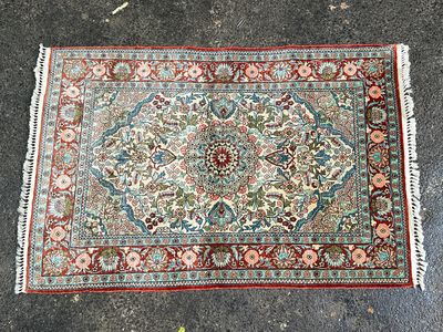 un tapis posé à même le sol, orné d'une bordure verte et rouge