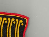 a black and red patch with gold writing on it