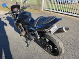 a black motorcycle parked in a parking lot next to a fence