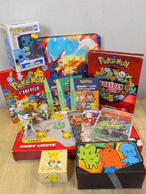 une pile de jouets et de jeux Pokémon posée sur une table en bois