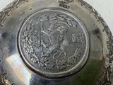 a silver plate with a coin on it on a table
