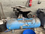a blue air compressor sitting on the ground next to a blue bucket