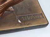 a bronze statue of a bird that is on top of a book