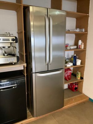 un réfrigérateur en acier inoxydable et une cuisinière noire dans une cuisine