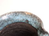 a close up of a blue vase on a white surface
