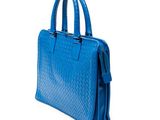 the blue handbag is sitting on a white surface