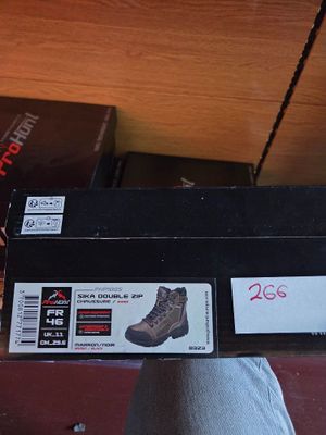 someone is holding a box with a pair of shoes on top of it