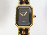 une montre noire et dorée, entourée d'une chaîne