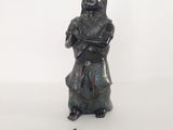 une ancienne figurine en bronze représentant une femme tenant un livre