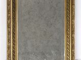 a mirror hanging on the wall with a gold frame