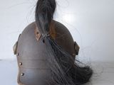 a brown helmet with a long black hair on top of it