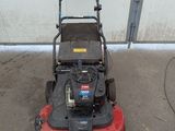 an image of a lawn mower parked in front of a garage