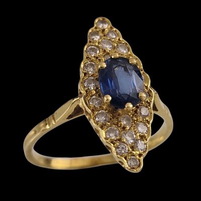 gros plan d'une bague en or avec un saphir et des diamants