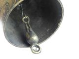 a metal bell hanging from the side of a pole
