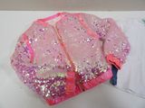 a pink jacket with sequins on it sitting on a table