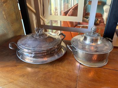 une paire de plats à gratin en métal argenté posés sur une table en bois, avec un miroir en arrière-plan