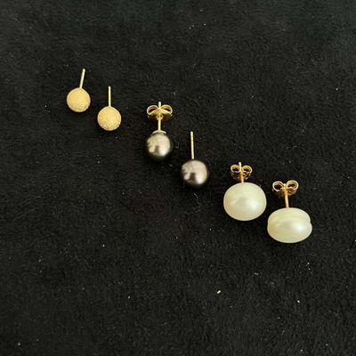 trois paires de boucles d'oreilles en perles et or sur fond noir