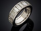 a white gold ring with baguets of diamonds on a black surface