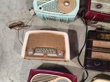 several old fashioned radio ' s are lined up on the floor