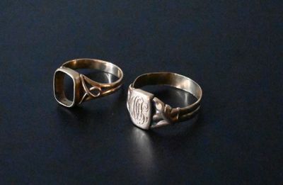 two silver rings with initials on them sitting on a table
