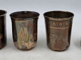 quatre tasses en métal de tailles différentes posées les unes à côté des autres sur une surface blanche