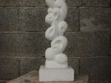 a white sculpture sitting on a wooden table next to a brick wall