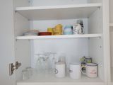 many cups and mugs on the shelves in the kitchen