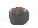 brown and black vase on a white surface with a white background