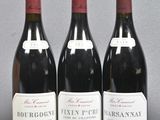 three bottles of red wine are lined up on a table