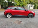 the red car is parked on the side of the road in the parking lot