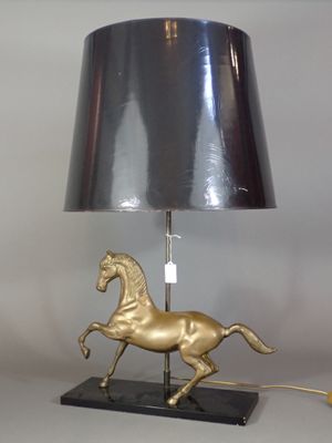 a gold horse lamp with a black shade on it