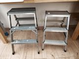 pair of metal step stools sitting on top of a hard wood floor