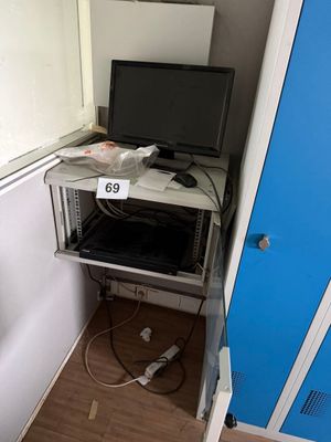 un bureau d'ordinateur sur lequel est posé un écran, dans un coin de la pièce