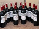 Plusieurs bouteilles de vin rouge sont alignées sur un plateau en bois