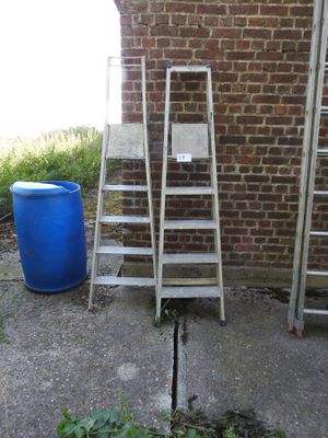 a ladder leaning against a brick wall next to a blue barrel