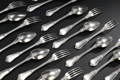 beaucoup de cuillères et de fourchettes en argent posées sur une table noire