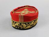 a red hat with gold trim on a white surface