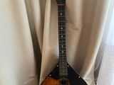 une guitare posée sur un support devant un rideau