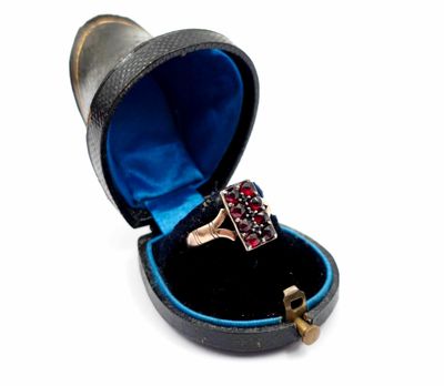 une bague dans un écrin noir, sertie d'une pierre rouge