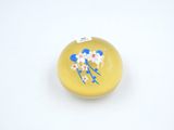 un petit objet jaune orné de fleurs bleues et blanches