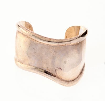un gros plan d'une manette argentée munie d'un manche en bois, posée sur une surface blanche