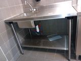 a stainless steel sink in the corner of a bathroom